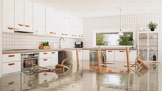 Flooded kitchen with standing water and chairs on the floor